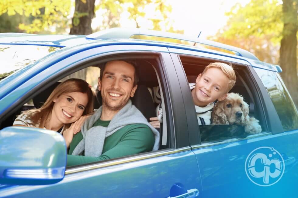 Smiling family and their dog in a freshly washed blue car